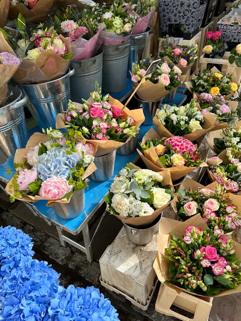 A variety of freshly arranged floral bouquets displayed outdoors, featuring pastel-colored flowers such as pink roses, white lisianthus, lavender, and light blue hydrangeas, all wrapped in brown kraft