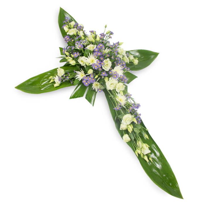 In this heartfelt memorial cross, every botanical choice conveys meaning: broad, shimmering green leaves form the foundational silhouette of the cross, their waxy surfaces and prominent veins giving the piece structure and life against a plain white surface. Concentrated at the centre and flowing outward along the arms are clusters of pale blooms-soft white and creamy ivory lisianthus whose layered, velvet-like petals and occasional closed buds offer a sense of unfolding grace. Complementary white spray chrysanthemums or similar small rounded flowers are nestled among the lisianthus, introducing gentle highlights and a quiet, garden-like texture. Threaded through these are numerous tiny lavender or light purple accents-limonium or aster-type blossoms-that introduce cool, contemplative notes and a delicate filigree across the floral mass. Scattered fine greenery softens transitions and breathes natural depth into the arrangement. The overall lighting is soft and even, lending the flowers a serene translucence while emphasizing the contrast between the glossy leaves and the feathery petals. The scent one might imagine is faintly green and floral, unobtrusive yet comforting. This composition is particularly suited to services and memorials in St James's and the surrounding streets-places where the community comes together in quiet remembrance. It reads as both a religious symbol and a personal tribute: dignified, compassionate, and crafted to offer consolation and enduring beauty at a time of loss.